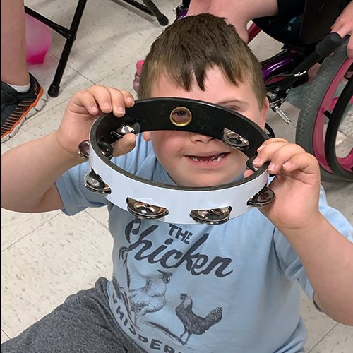 A young boy looks through a tamborine