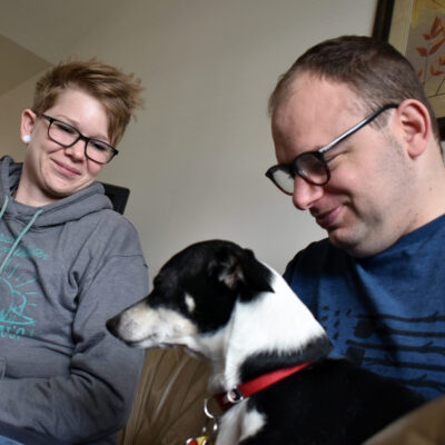 A man holds a small dog while a woman looks on