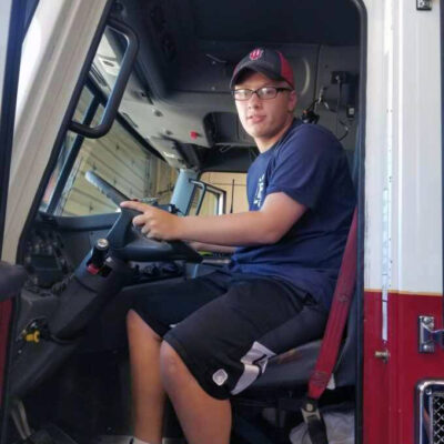 A teen boy sits in a fire truck