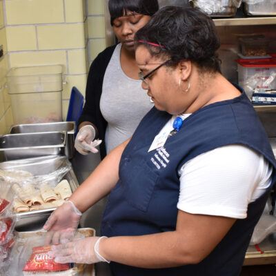 A young woman packages a lunch in a commercial kitchen