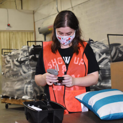 A young woman in face mask scans a tag for a pillow