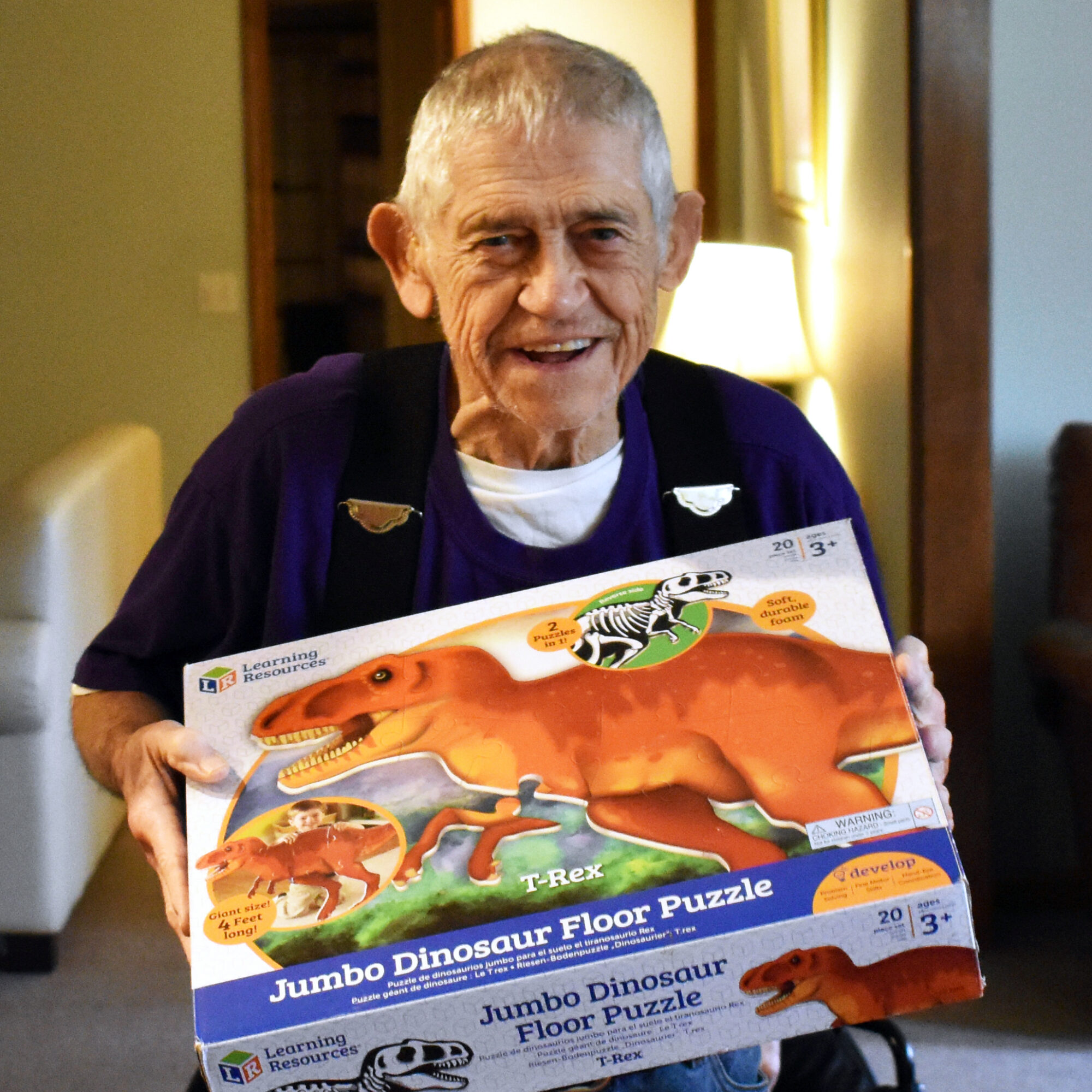 GH-Marlin | Easterseals Northeast Indiana A senior man smiles and holds up a dinosaur puzzle box