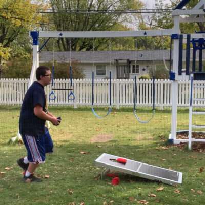 A young man tosses a bean bag