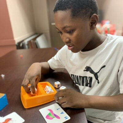 A young boy uses a Boggle game to spell words