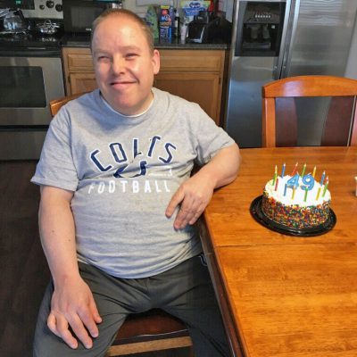 A man smiles next to a birthday cake