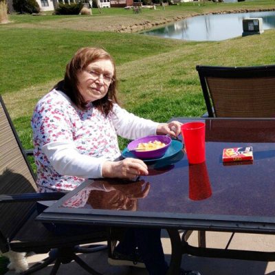 A woman eats a meal at a backyard patio table