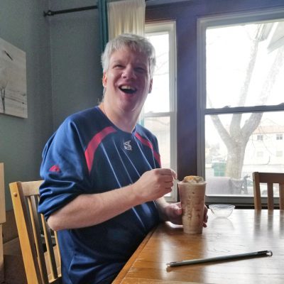 A man smiles while enjoying a frozen coffee drink