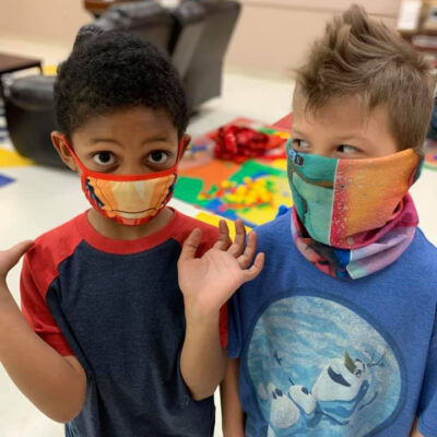 minis-2-boys A young boy wearing a face mask glances at another young boy in face mask
