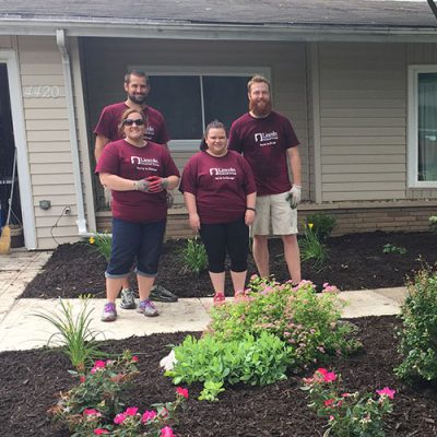volunteer-landscape Four volunteers in Lincoln Financial T-shirts pose by landscaping