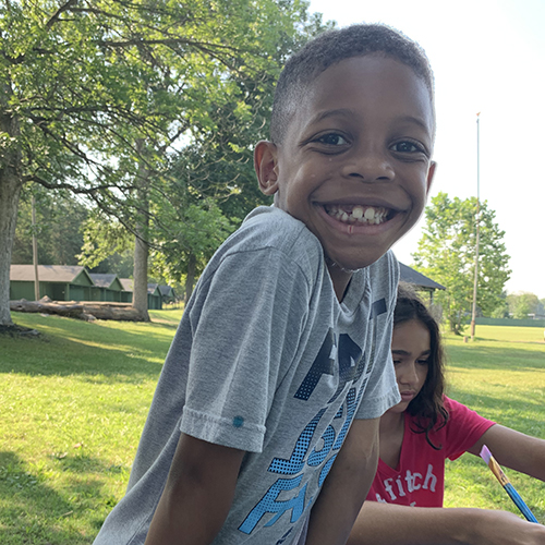 A young boy smiles at the camera