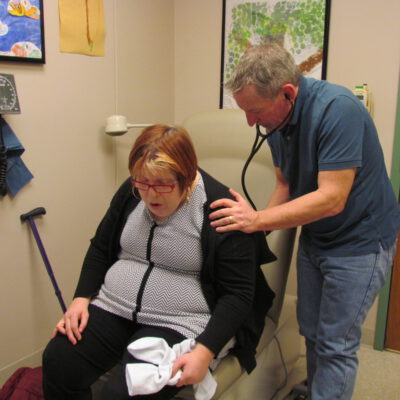 A doctor is checking a woman's breathing with a stethoscope