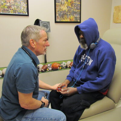 Doctor is talking to a patient while holding their hand.