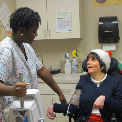 Whitney smiles up at a Nurse Asia while she takes her temperature.