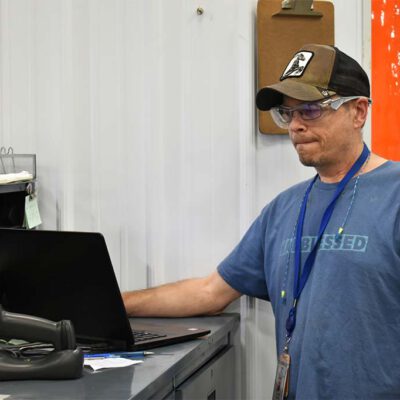 Chris updates an inventory spreadsheet on a computer at Fort Wayne Metals.